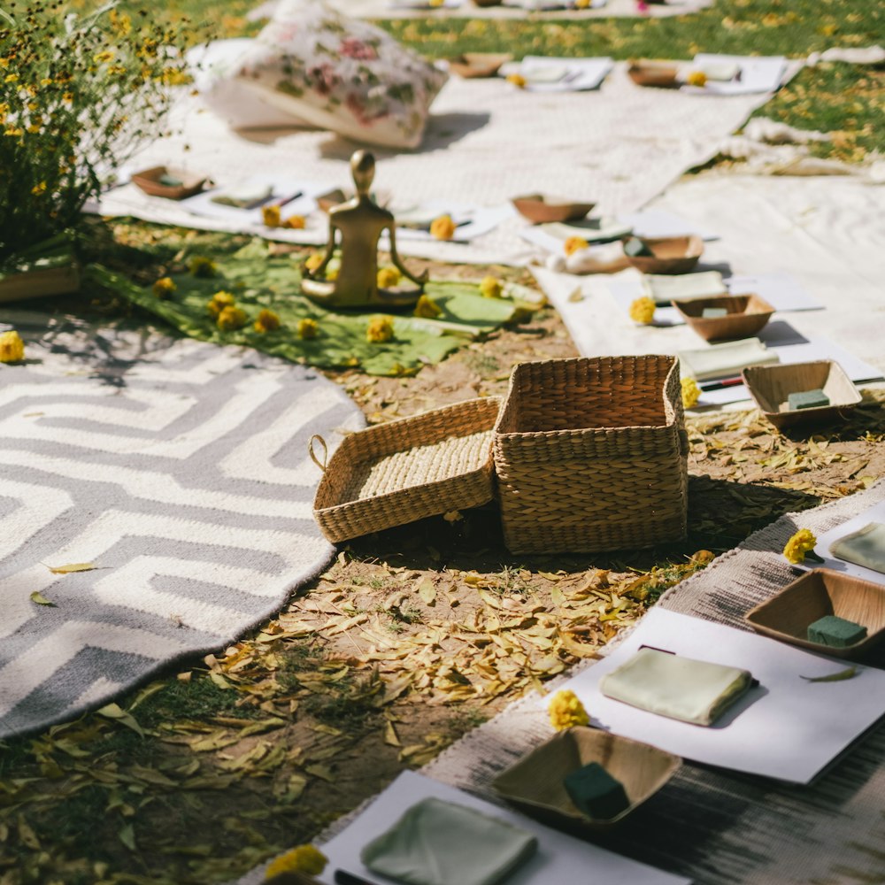 a picnic setting with wicker chairs and plates on the ground
