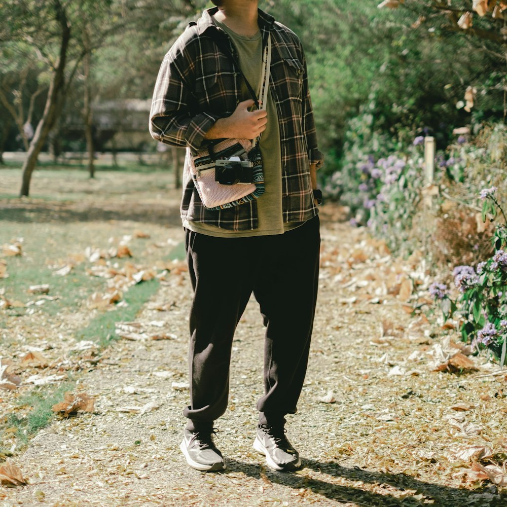 a man standing on a dirt road holding a camera