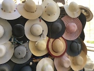 A collection of colorful hats displayed on a vintage rack by the window.