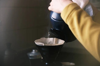 Close-up of a barista carefully pouring hot water over coffee grounds in a V60 dripper.