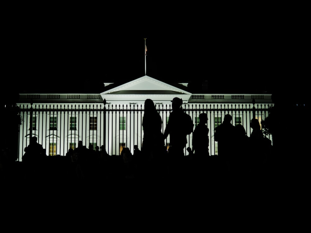 a group of people standing in front of a white house