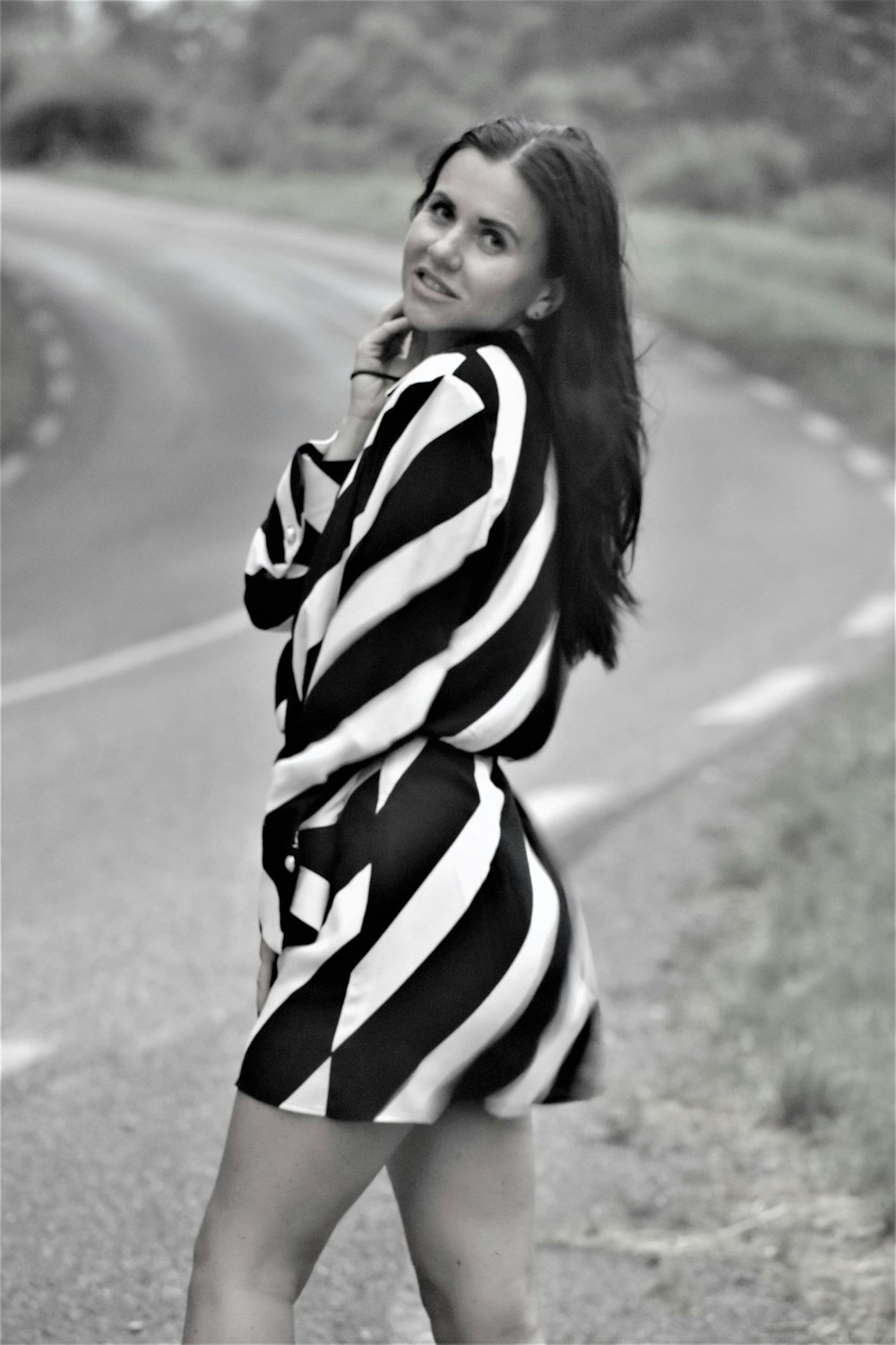 a woman in a striped dress standing on the side of a road