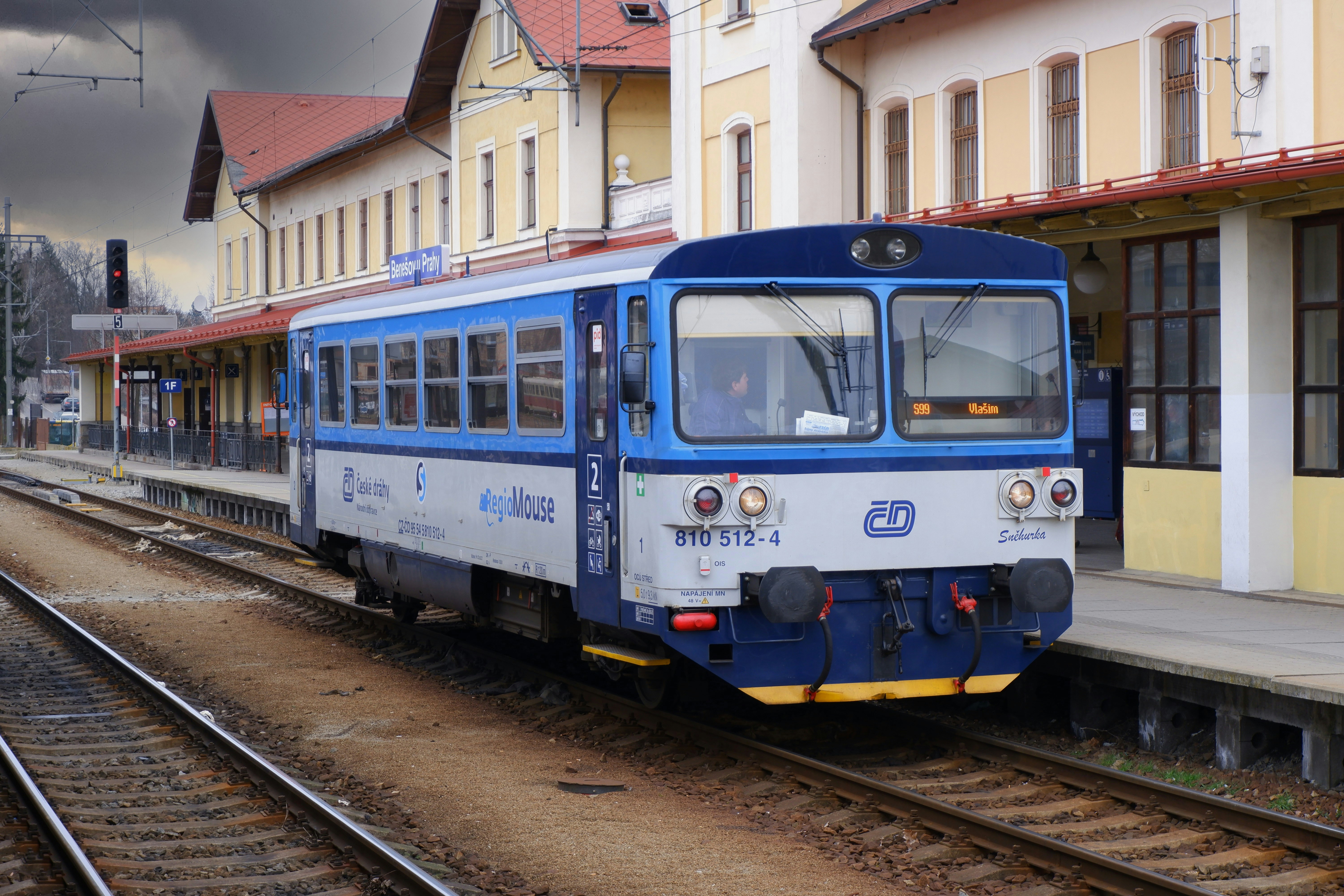 a blue and white train traveling past a train station