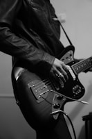 An artistic shot of a musician in a leather jacket against a gingham backdrop.