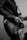 A person wearing a leather jacket plays an electric guitar. The focus is on the hands holding the guitar and the intricate details of the instrument's body, such as the strings, knobs, and pickguard. The image is in black and white, adding a classic and moody feel.
