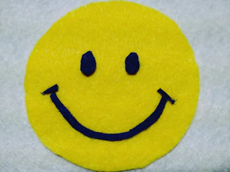 A bright yellow rounded card with a laughing emoji and playful purple accents on a soft white background.