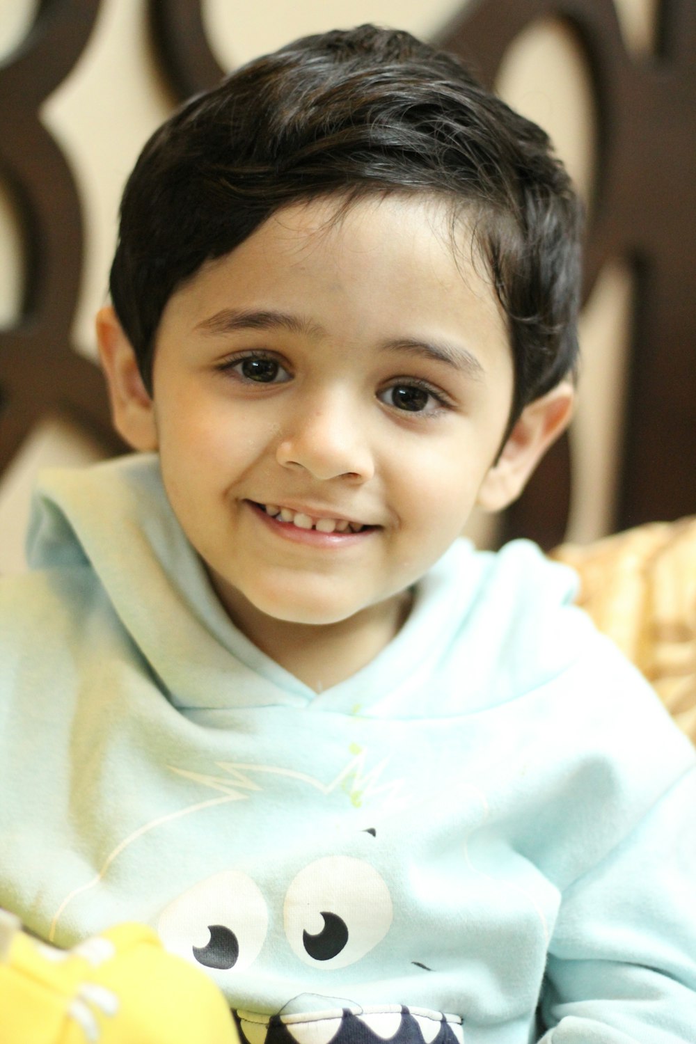 a little boy sitting on a chair with a stuffed animal