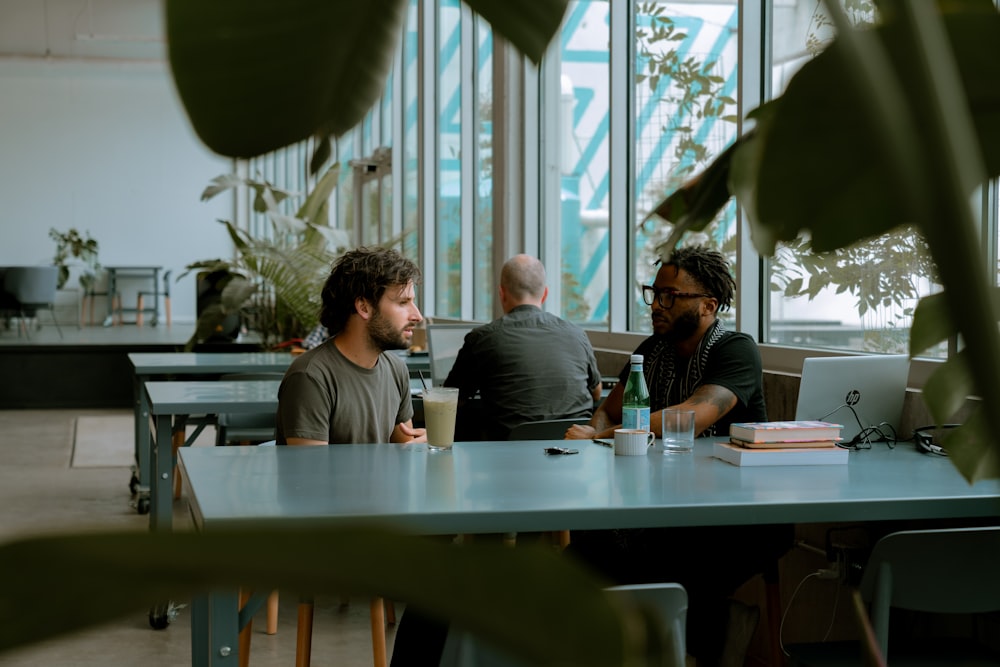 two men sitting at a table with a laptop