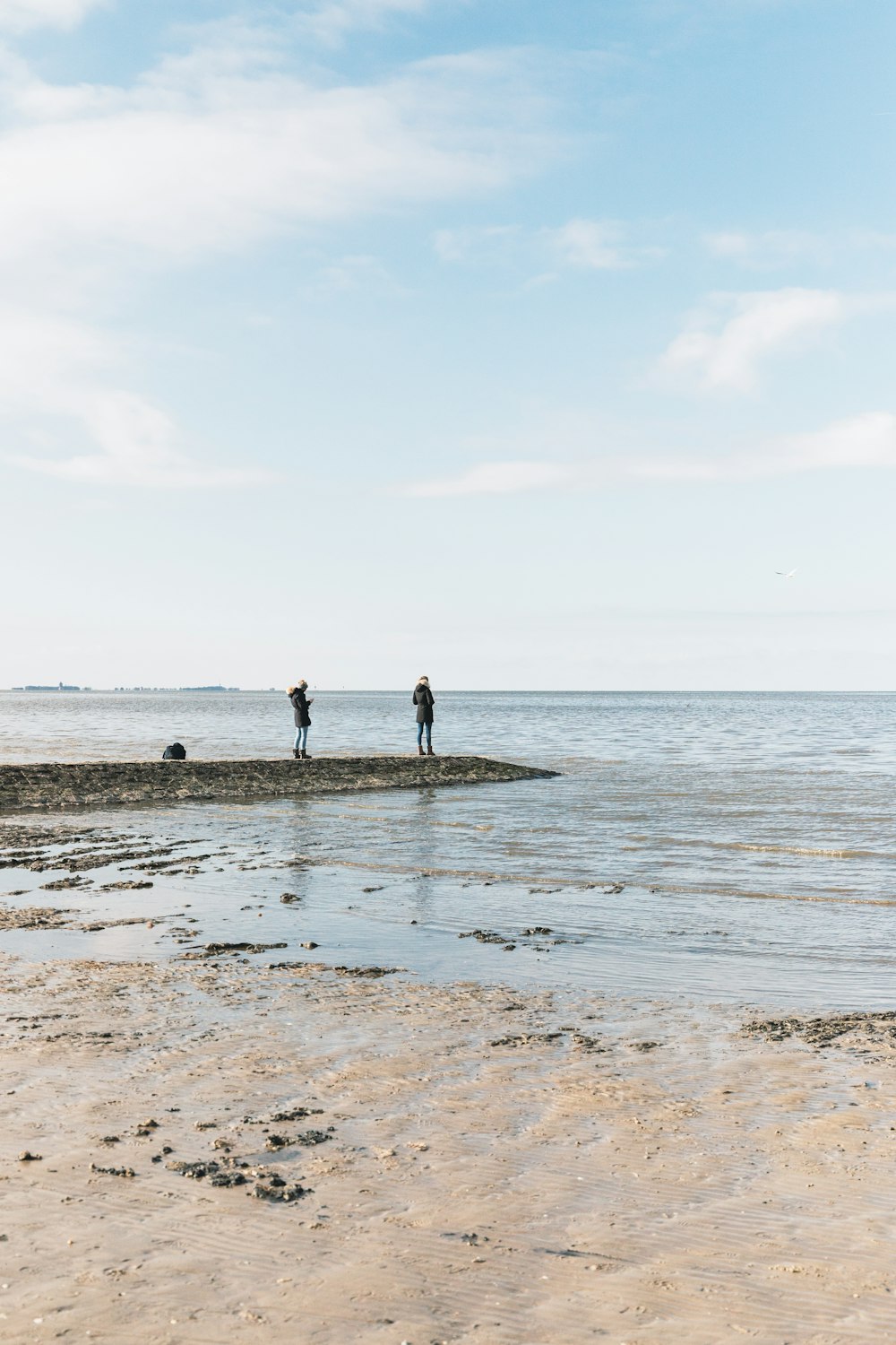 a couple of people standing on top of a sandy beach