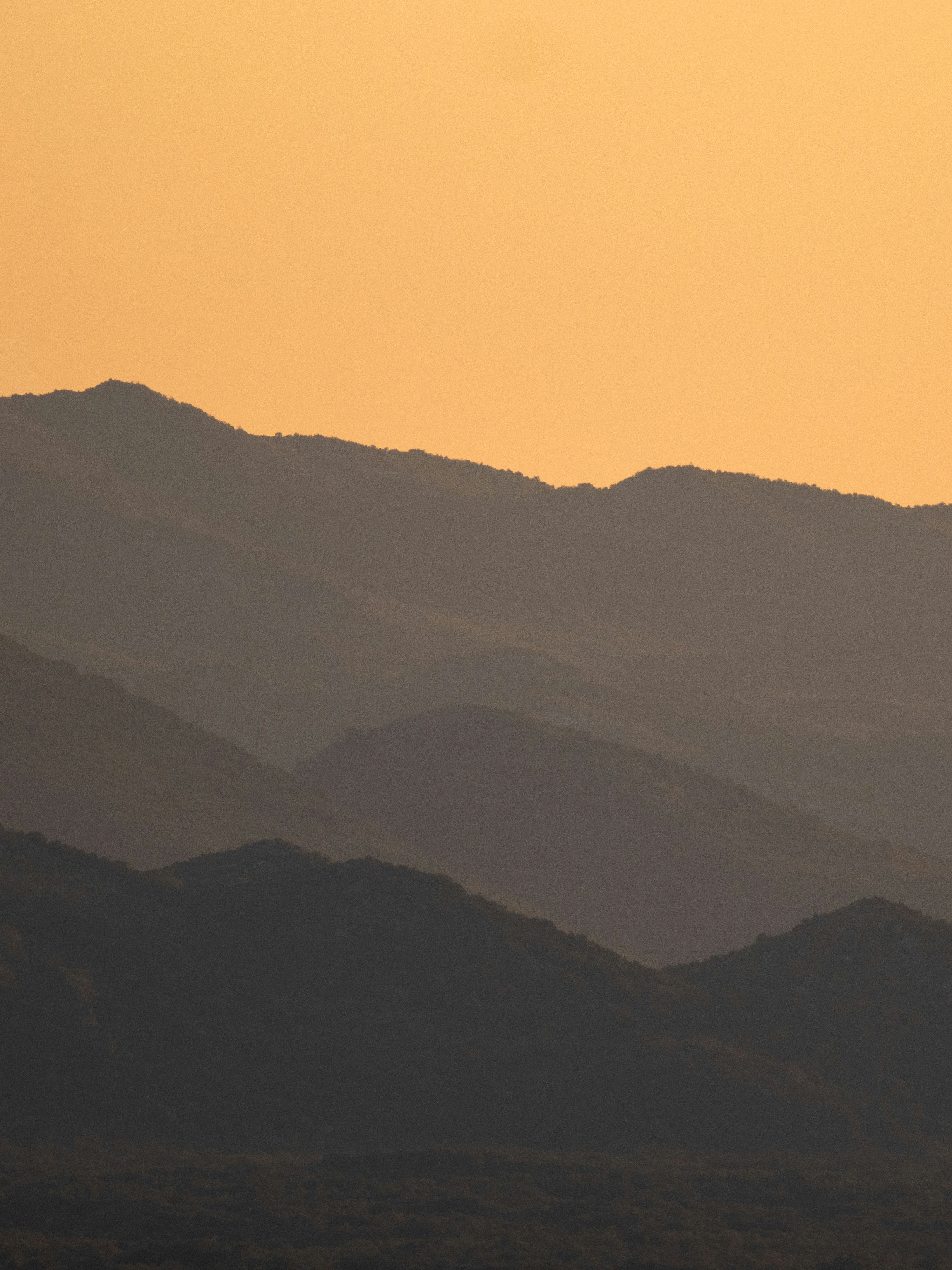a plane flying over a mountain range at sunset
