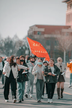 A diverse group of people walking together outdoors, wearing foundation t-shirts and holding banners about lung cancer awareness.