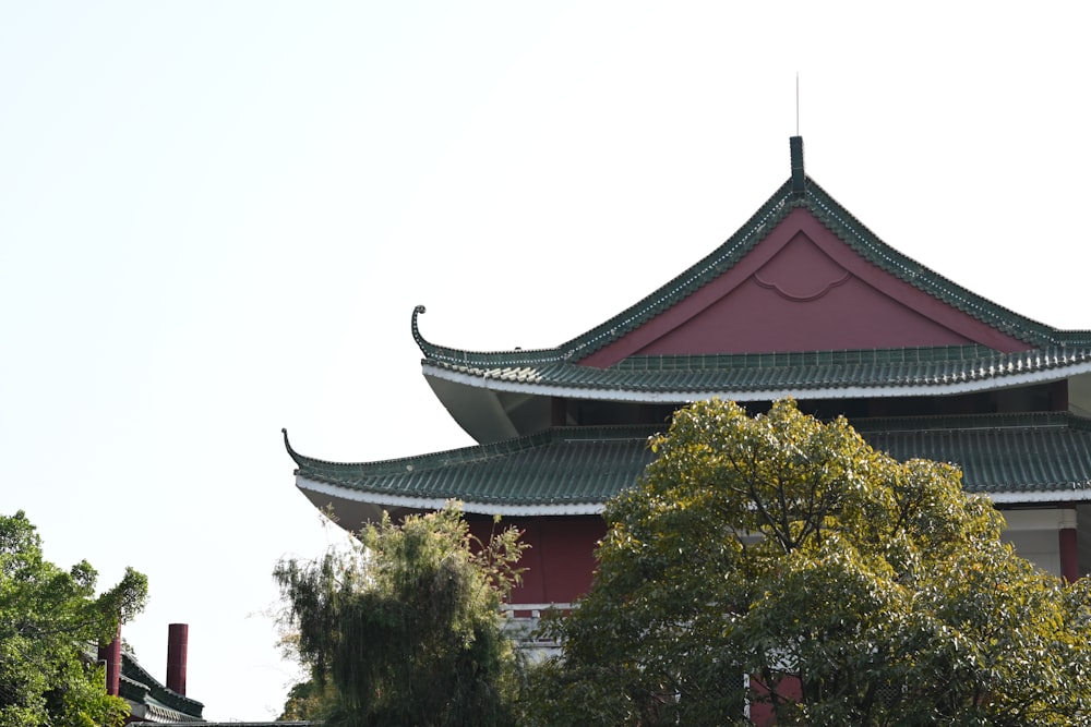 a tall building with a green roof surrounded by trees