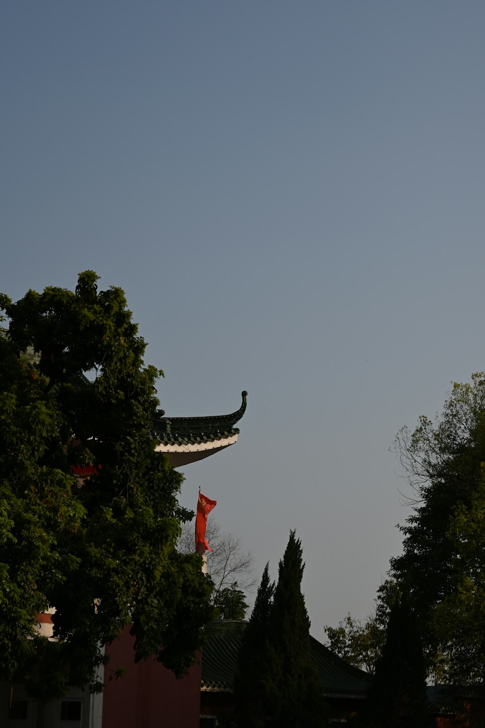 a building with an oriental roof and a tree in front of it