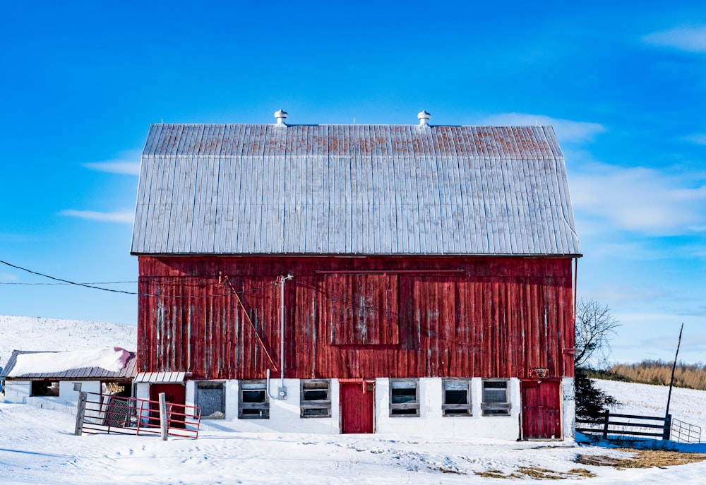 a red barn in the middle of a snowy field