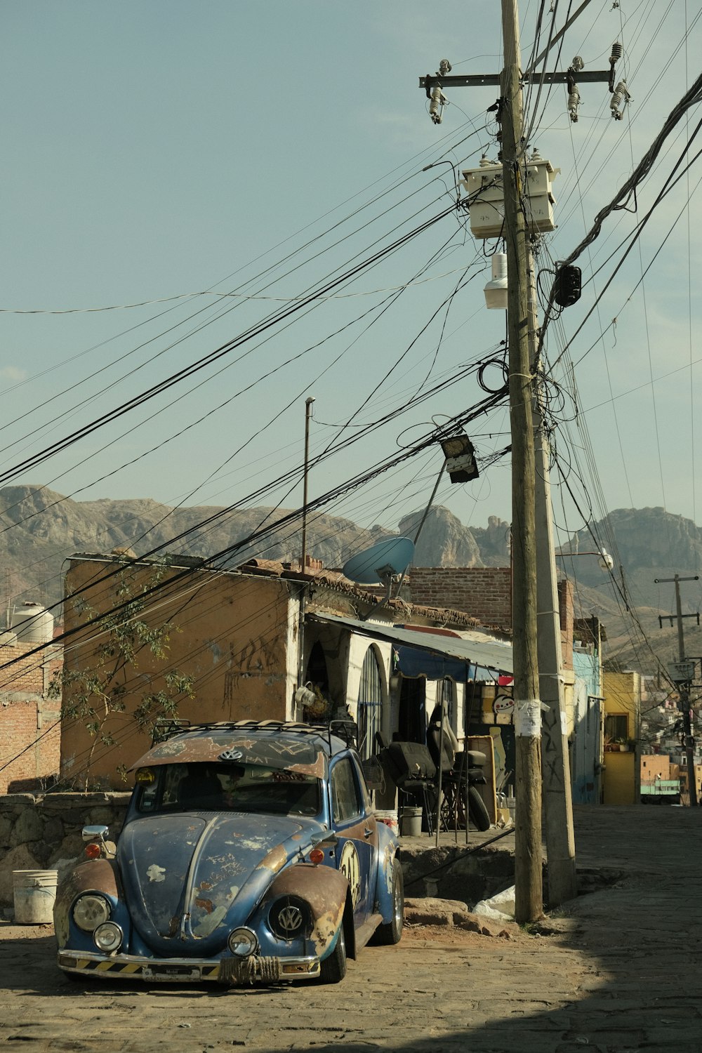 an old vw bug is parked on the side of the road