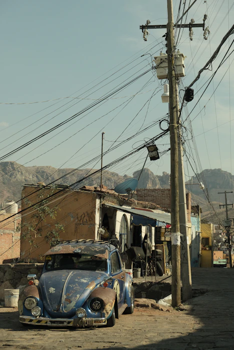 an old vw bug is parked on the side of the road