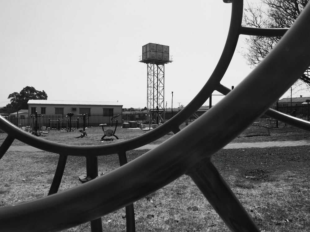a black and white photo of a playground with a water tower in the background