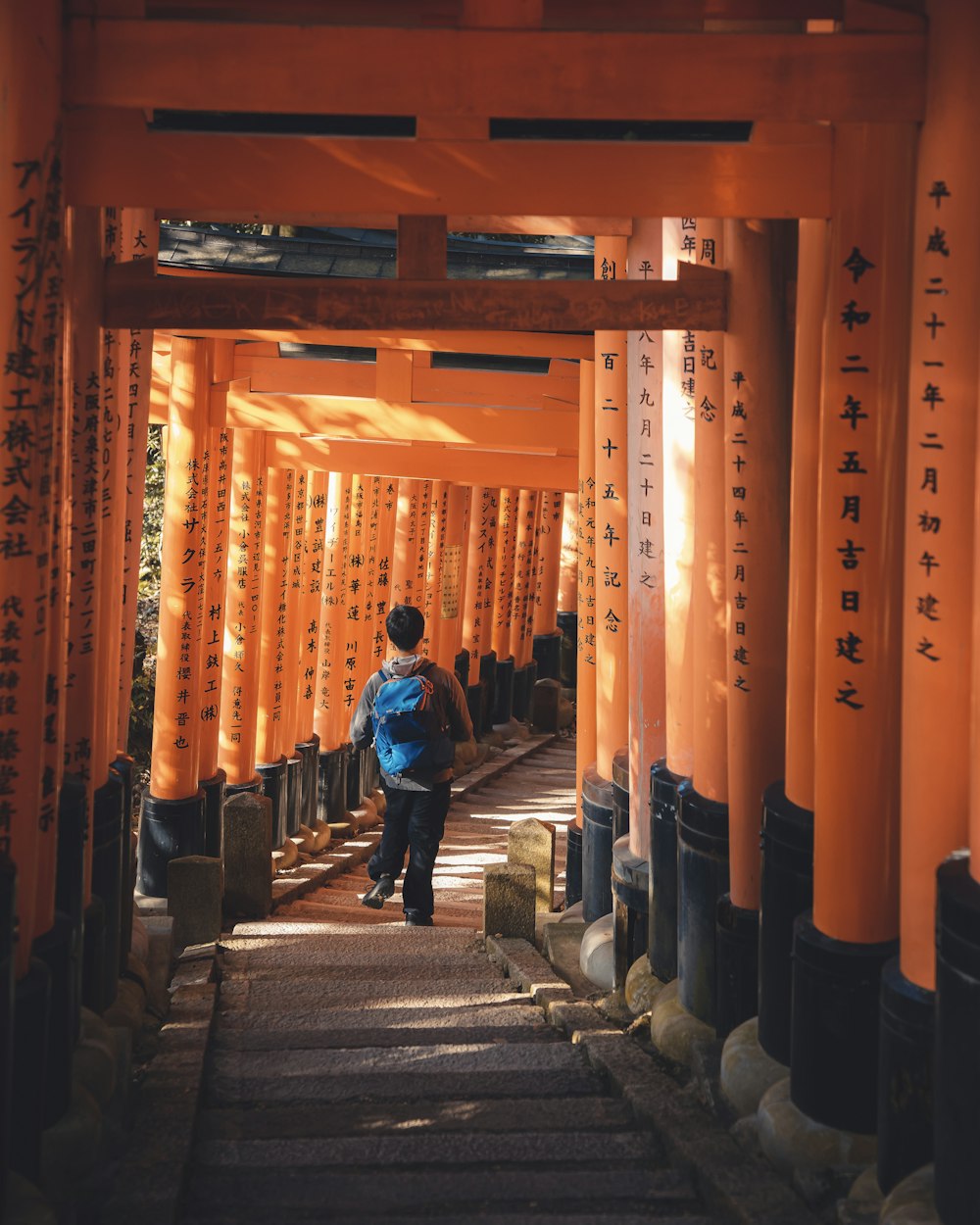 a person walking down a path lined with orange pillars