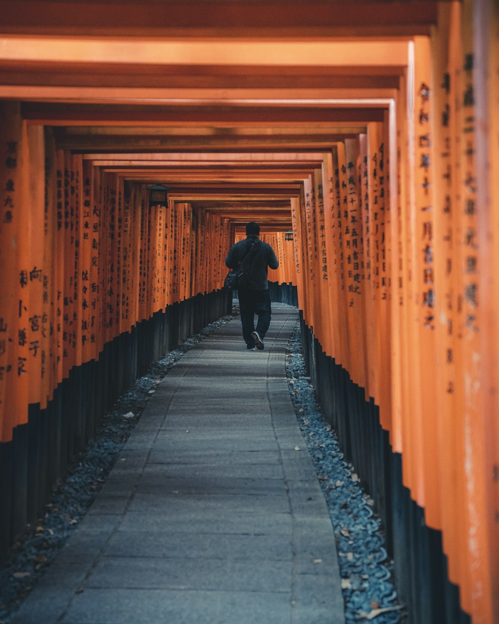 a man walking through a tunnel of orange tori tori tori tori tori tori tori tori