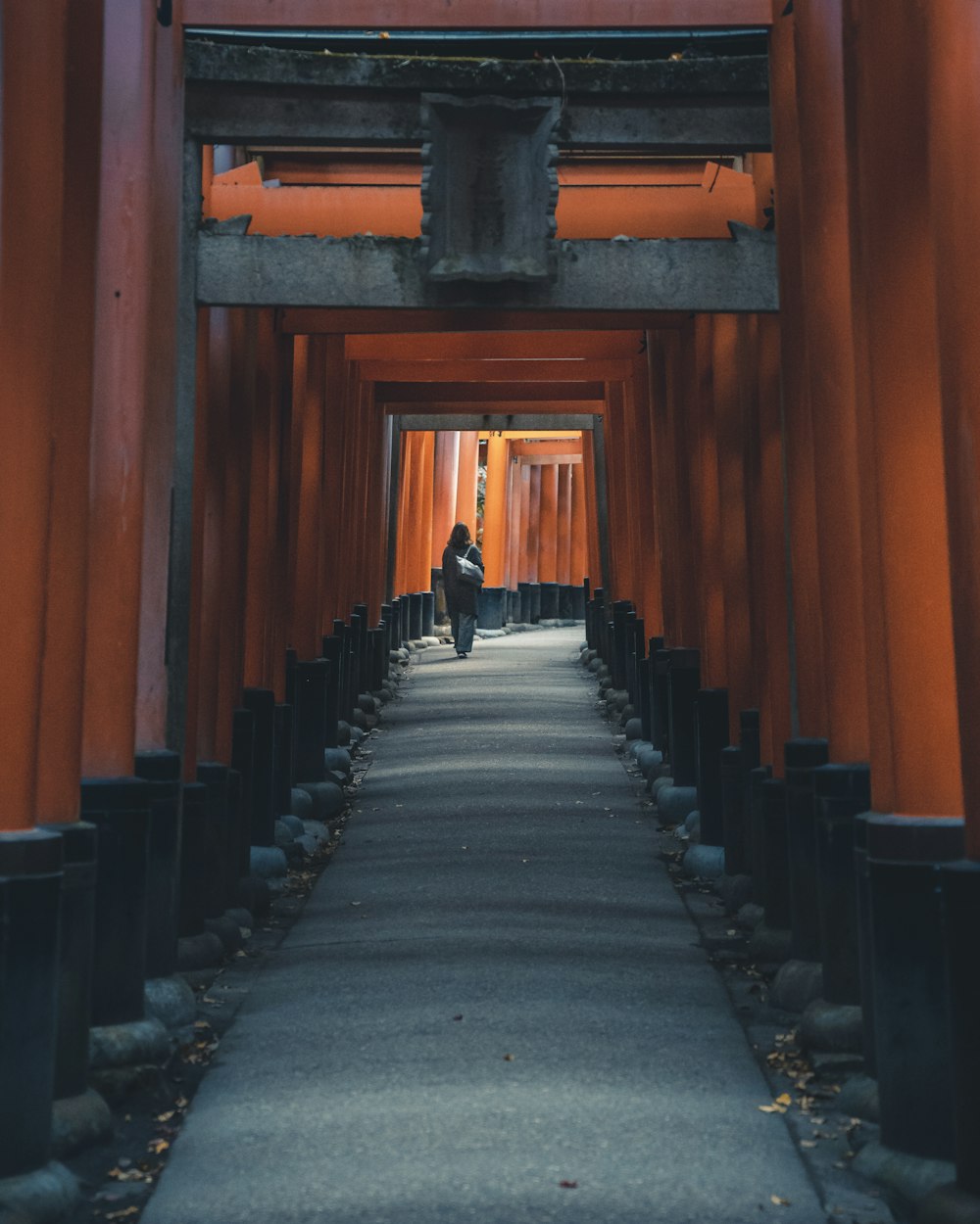 a person walking through a tunnel of red tori tori tori tori tori tori tori tori