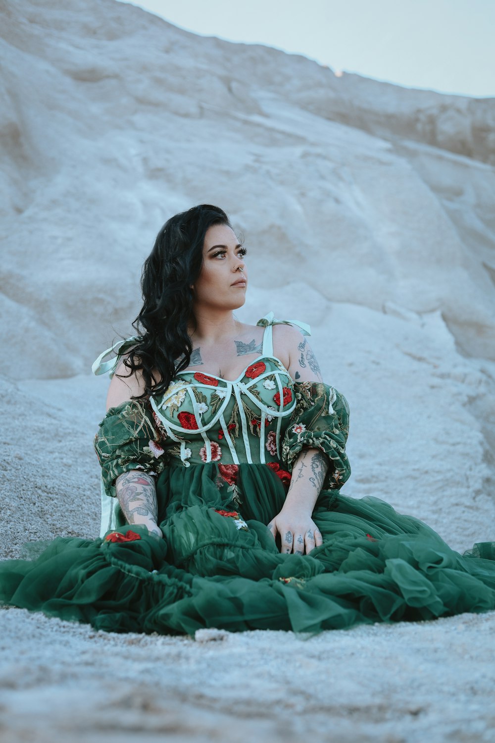a woman in a green dress sitting on the ground