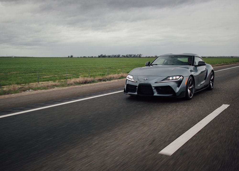 a gray sports car driving down the road