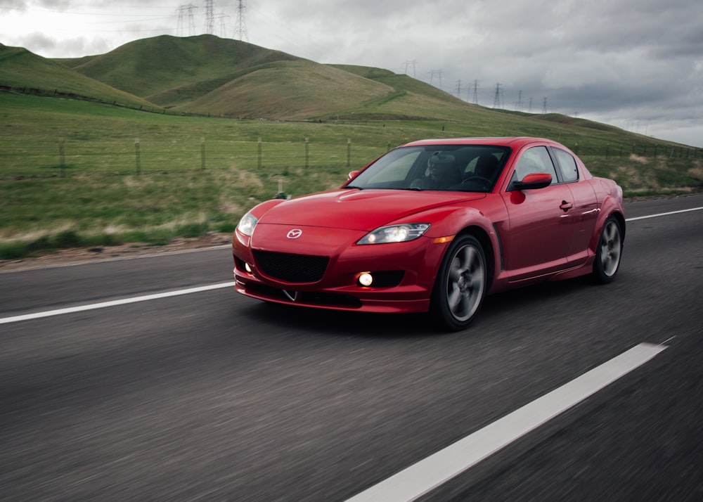 a red sports car driving down the road