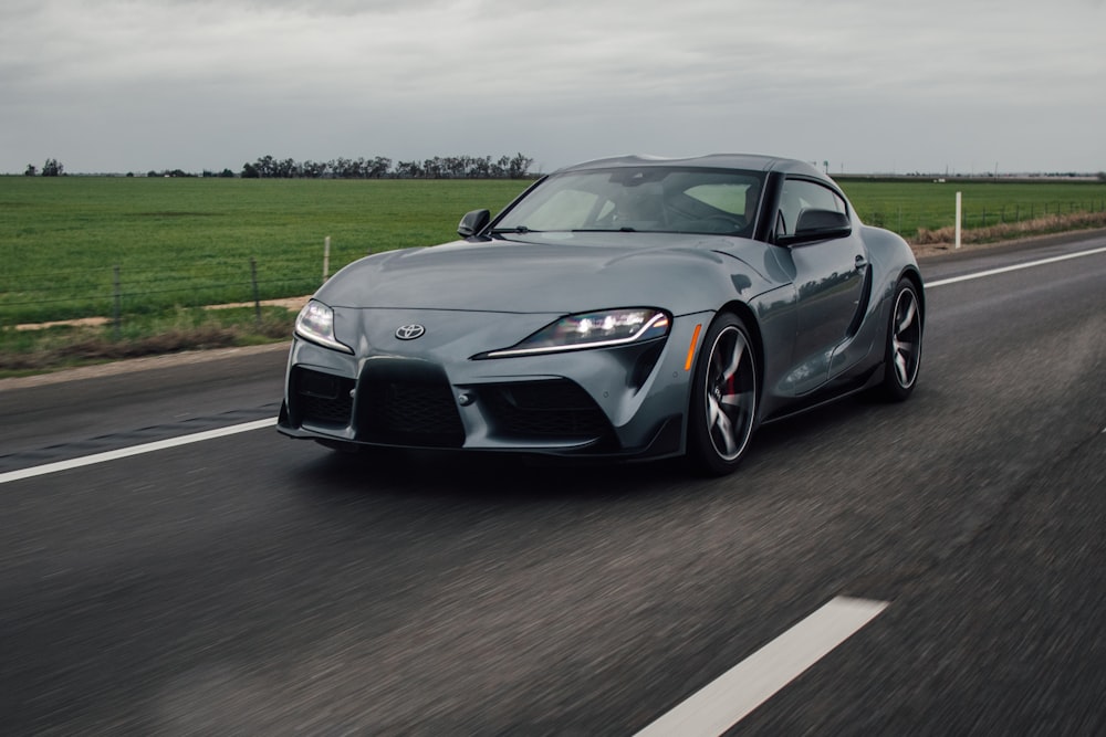 a gray toyota sports car driving down a road