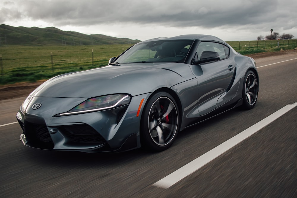 a gray toyota sports car driving down a road