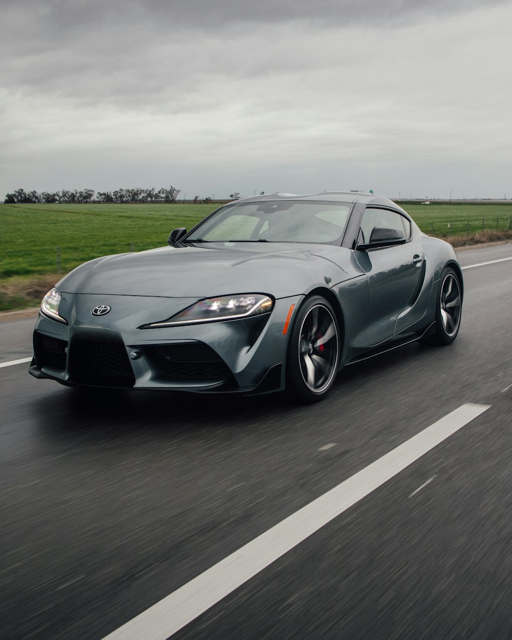 a gray toyota sports car driving down a road