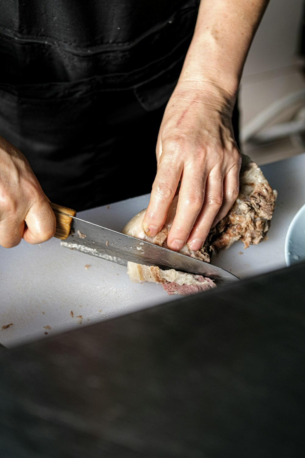 a person cutting meat with a knife on a cutting board