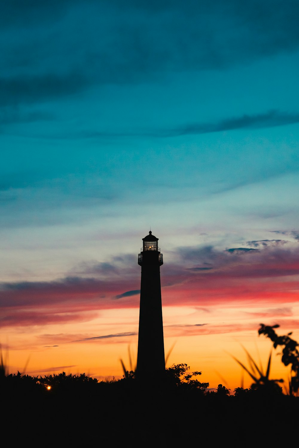 a lighthouse is silhouetted against a colorful sunset