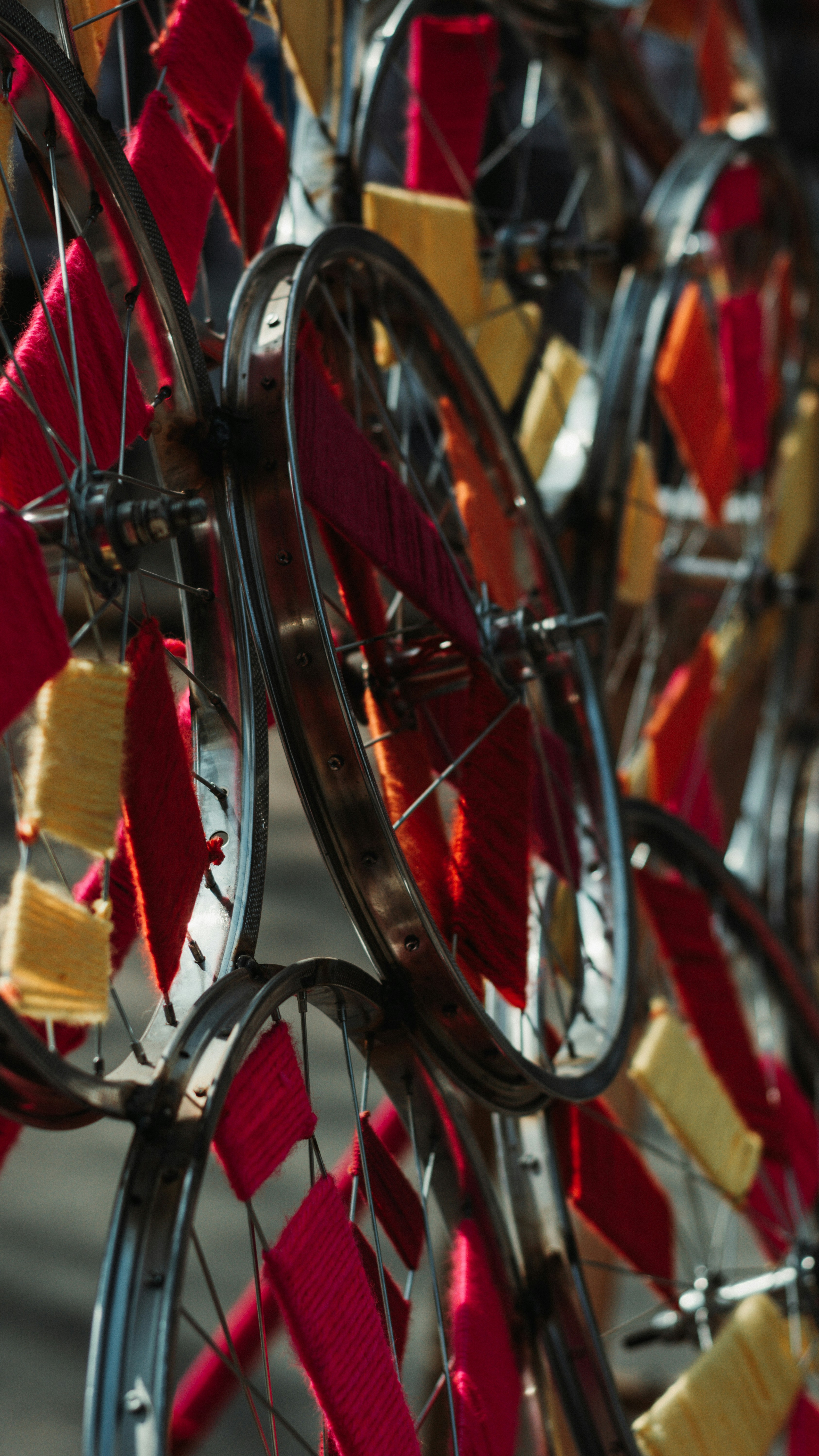 A close up of a bicycle wheel with red and yellow ribbons attached to ...