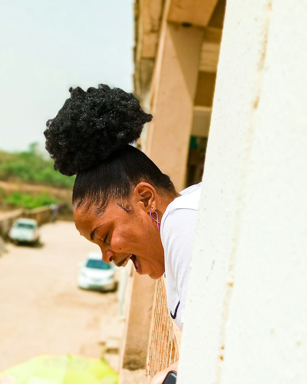 a woman leaning against a wall with her hair in a bun