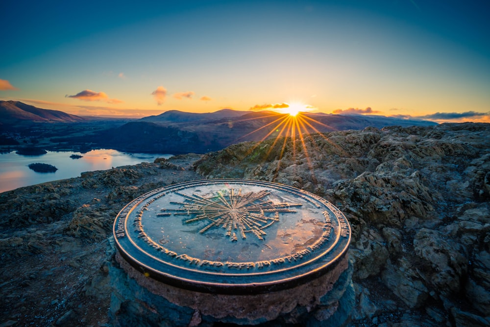 a sun setting over a mountain with a clock on it
