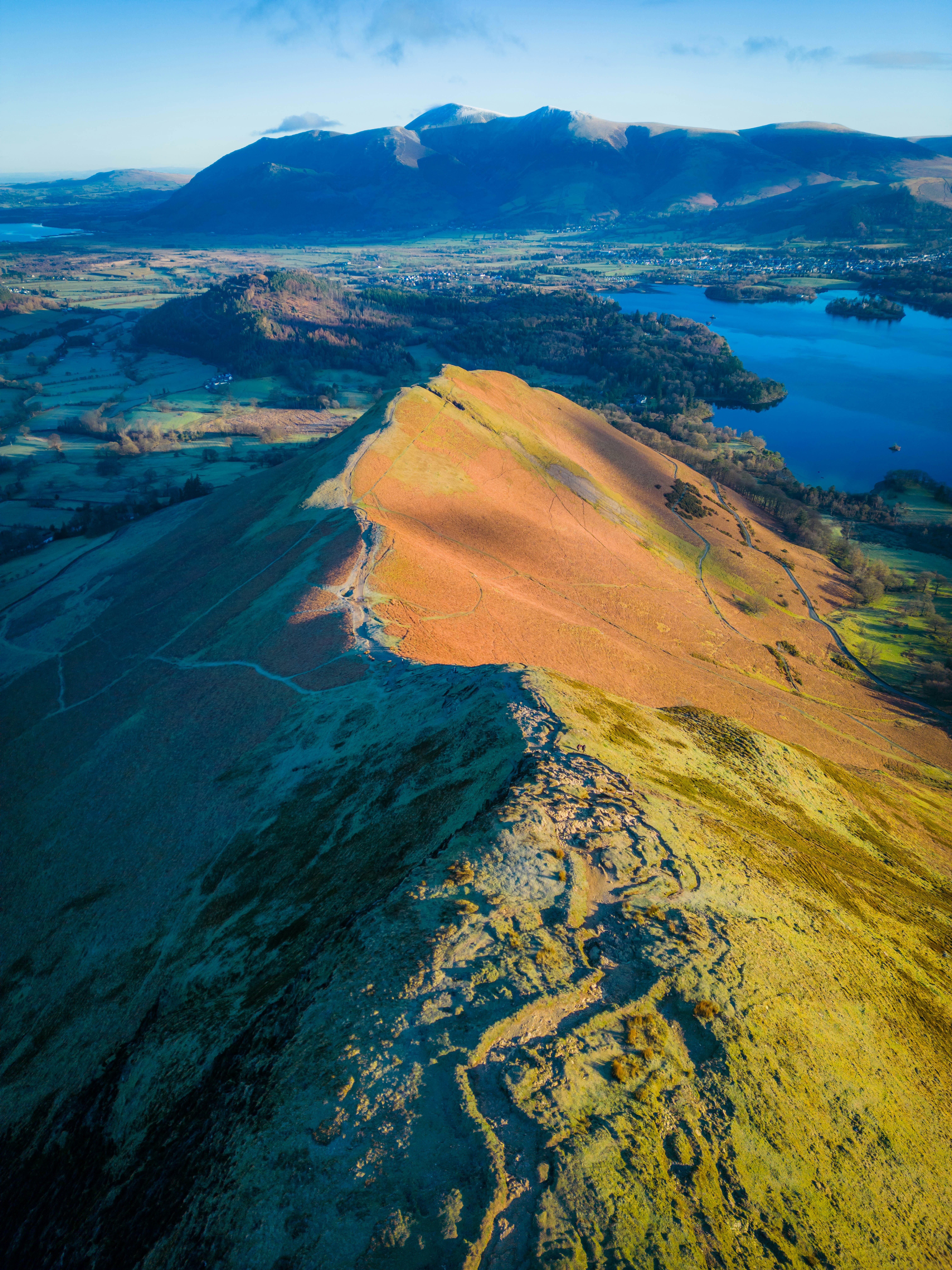 an aerial view of a mountain range with a lake and mountains in the background