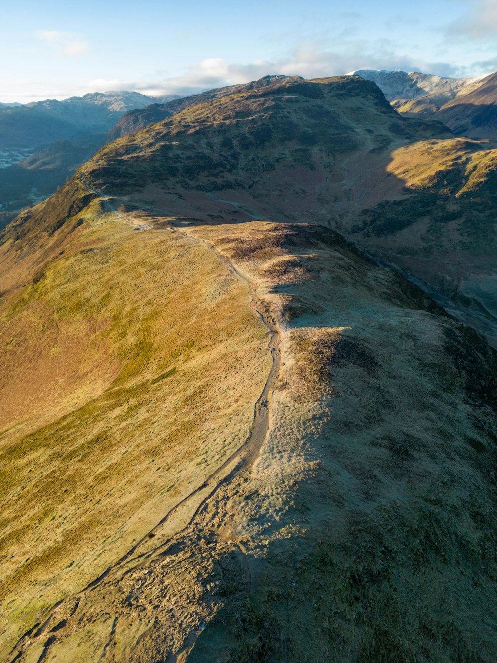 an aerial view of a grassy hill with mountains in the background