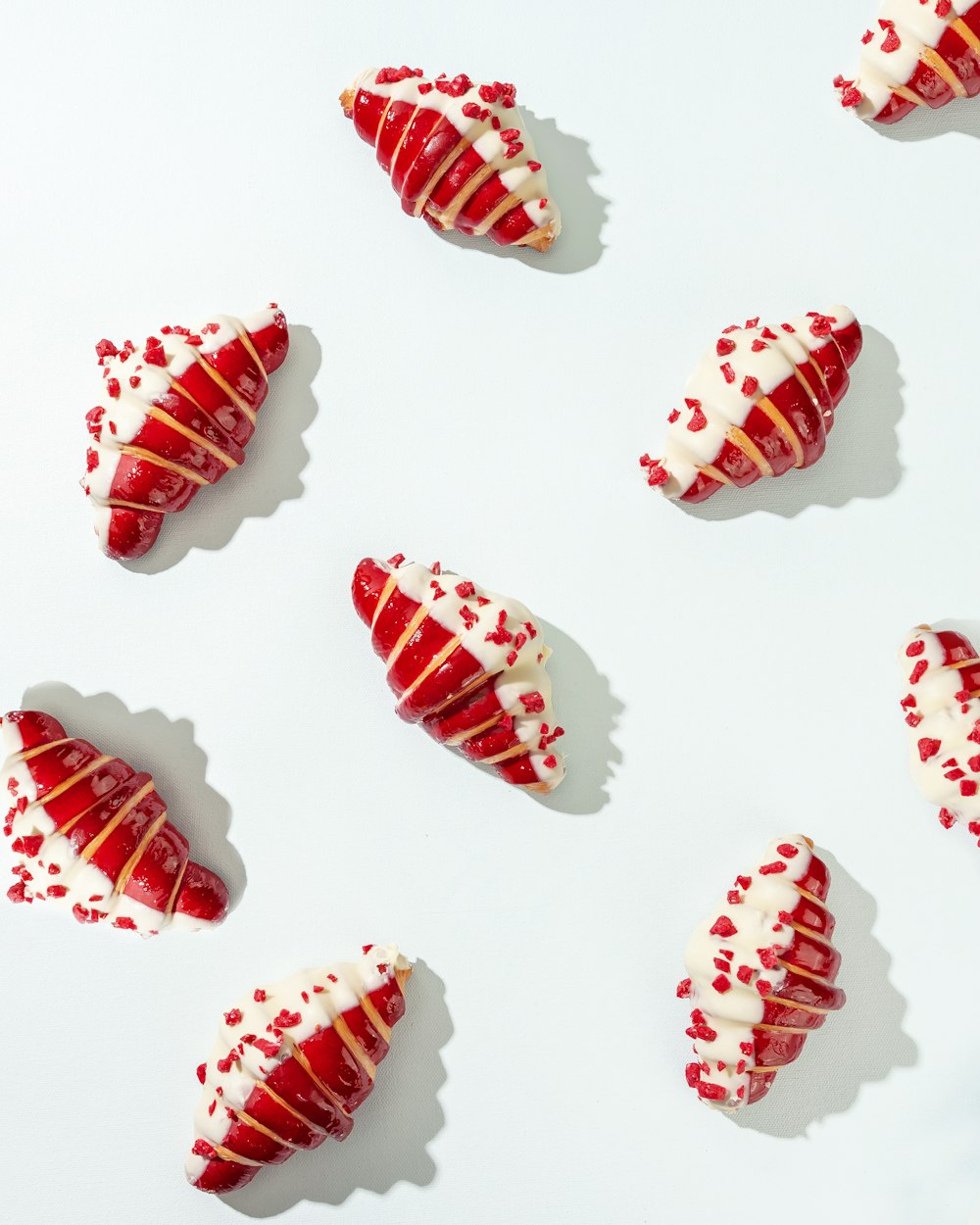 a group of red and white pastries on a white surface