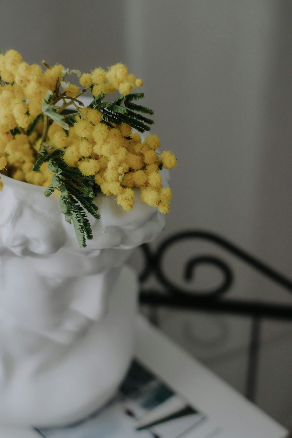 a white vase filled with yellow flowers on top of a table