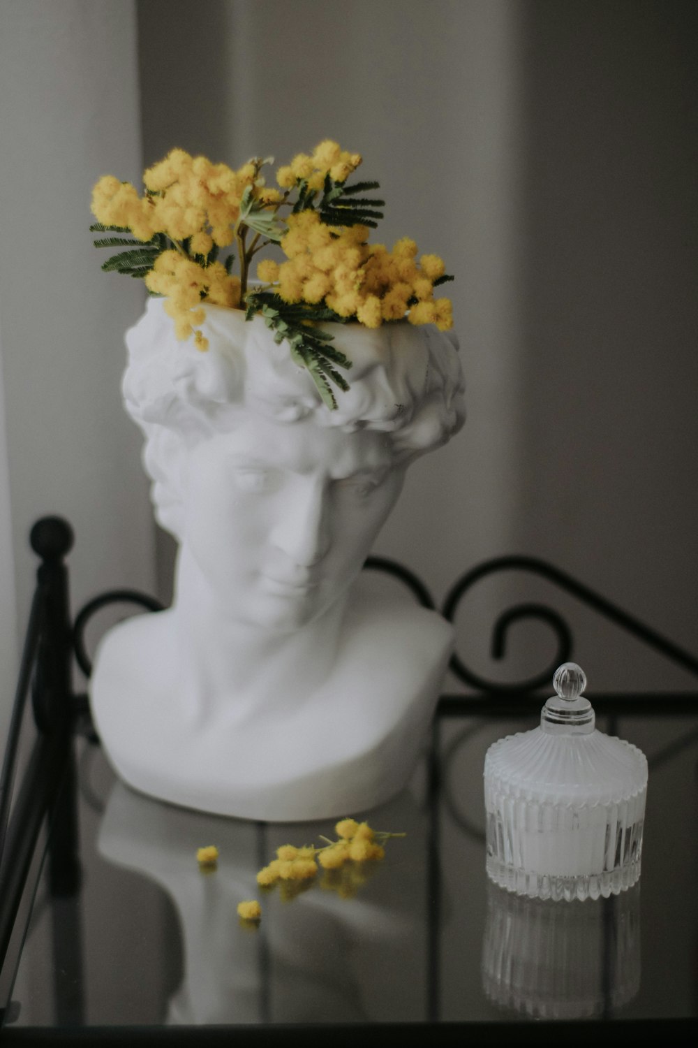 a vase with yellow flowers on top of a glass table