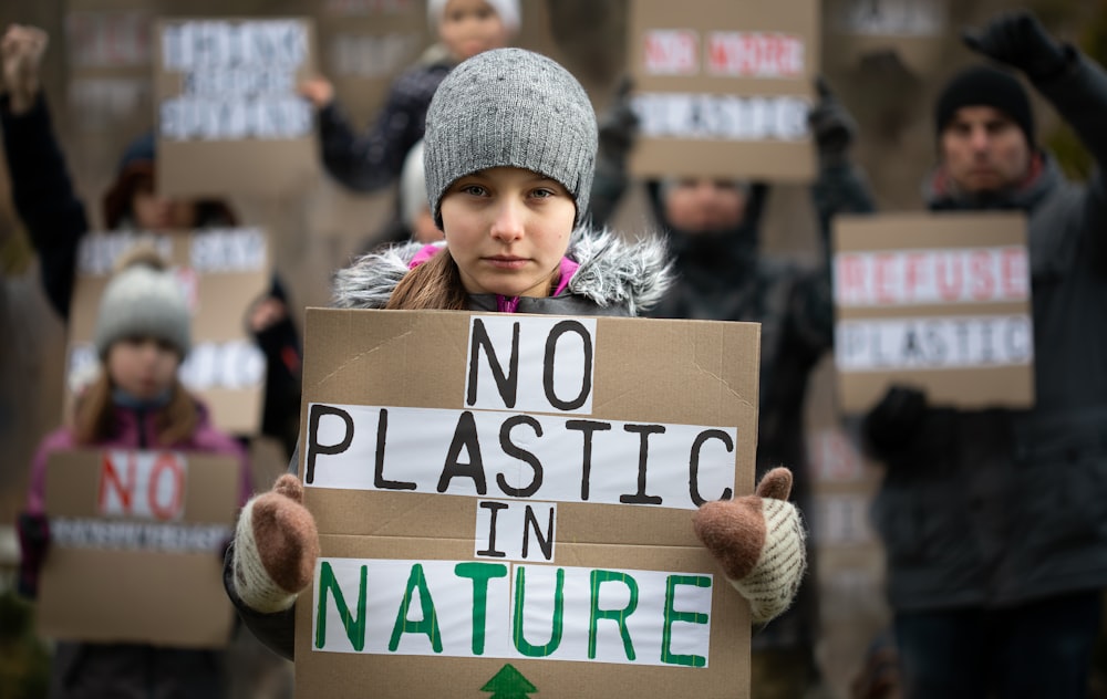 Una niña sosteniendo un cartel que dice que no hay plástico en la naturaleza