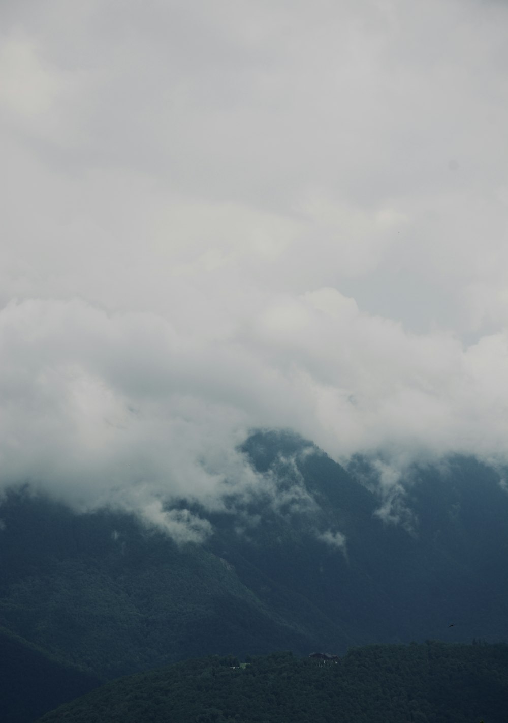 a plane flying over a mountain range under a cloudy sky