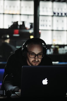 A focused CPA candidate studying with headphones and laptop in a bright, modern workspace.