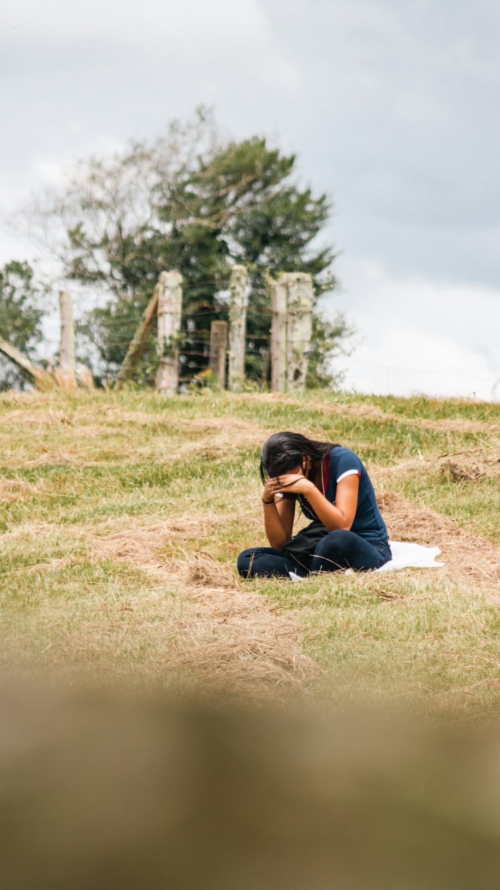 a woman sitting on the ground with her head in her hands