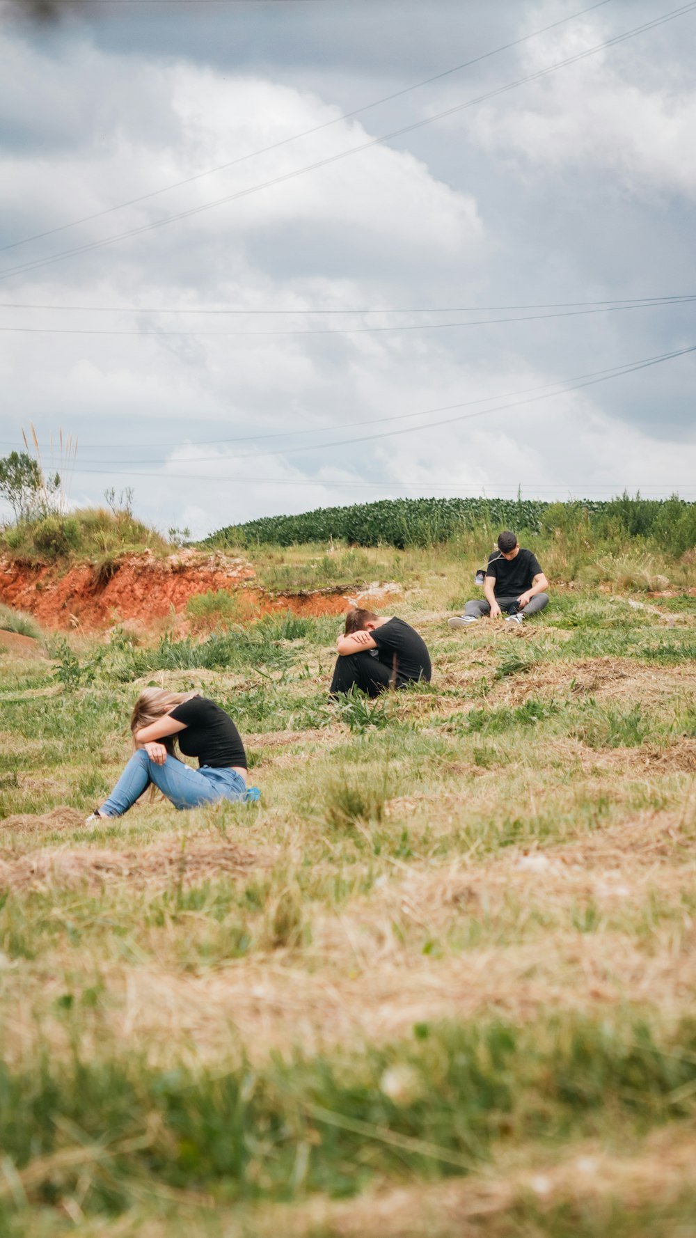 a group of people sitting on top of a grass covered field