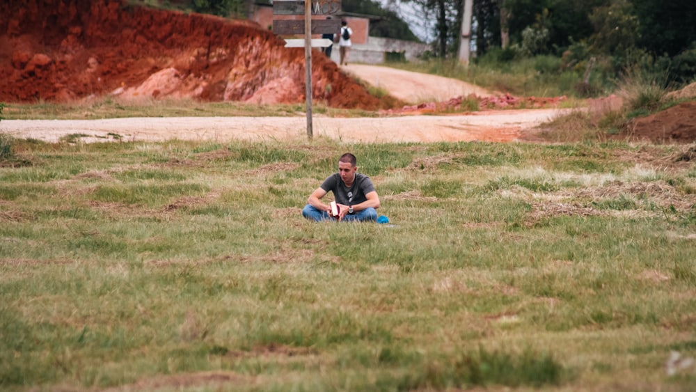 a man sitting in a field with a frisbee