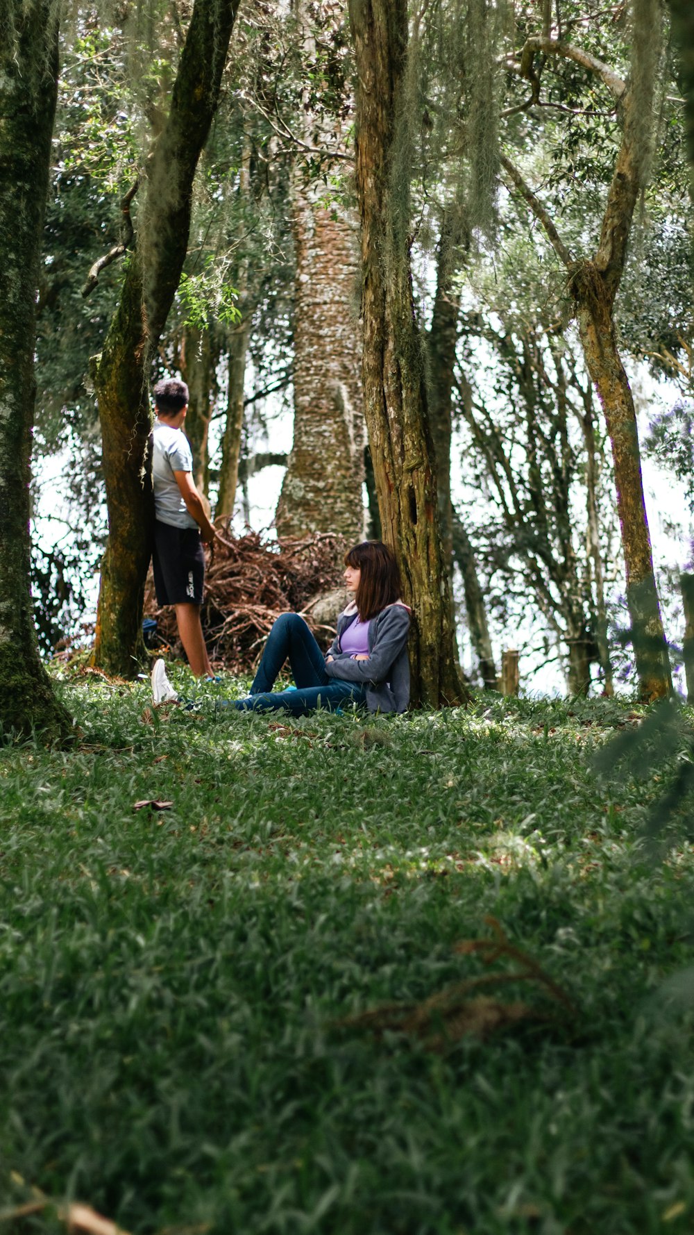 two people sitting on the ground in the woods
