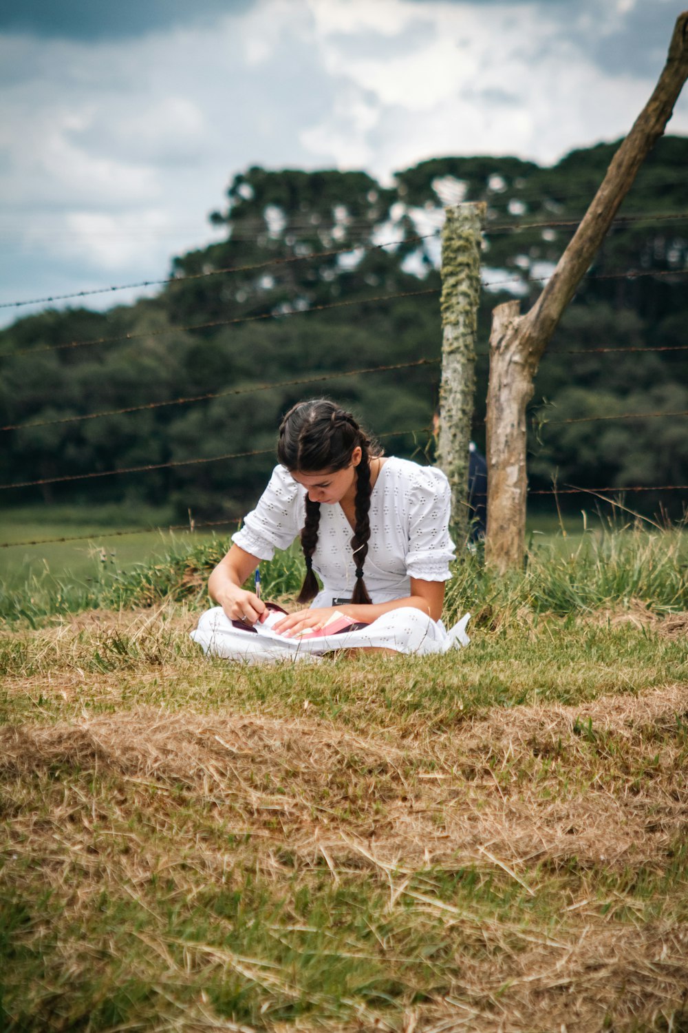 a woman sitting on the ground in a field