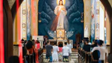 A group prayer session inside the church sanctuary with warm gold lighting.