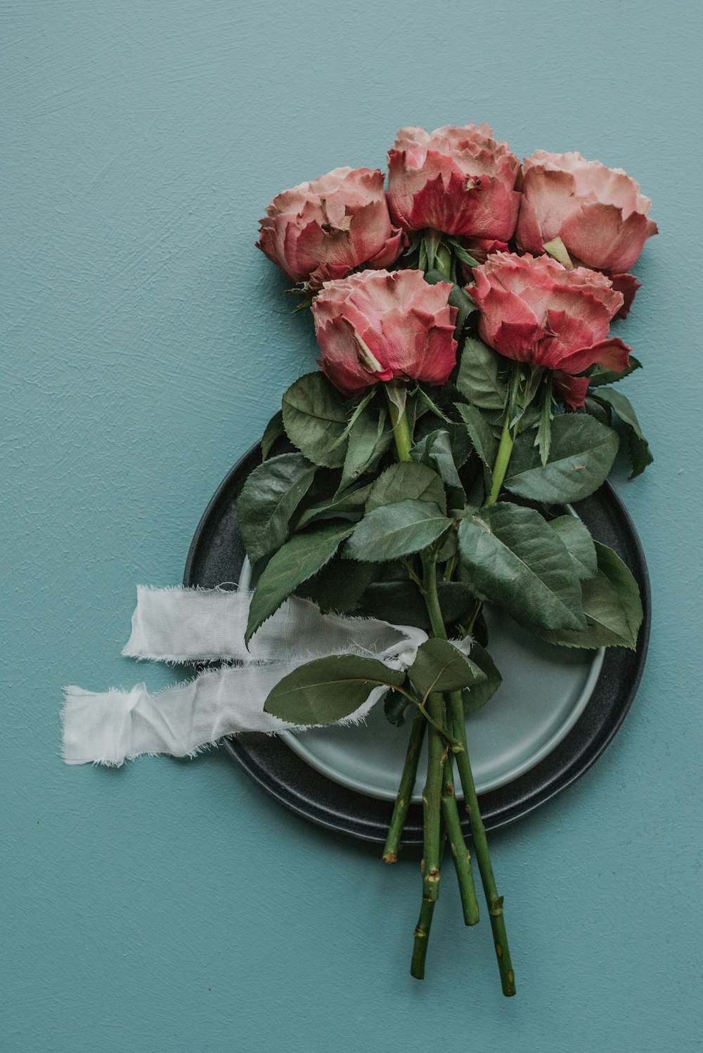 a bunch of pink roses sitting on top of a plate